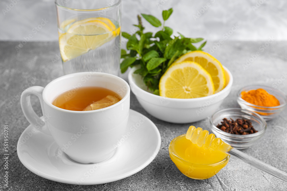 Cup with delicious immunity boosting tea and ingredients on grey table Cup with delicious immunity boosting tea and ingredients on grey table