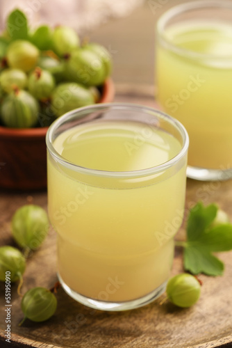 Tasty gooseberry juice and fresh berries on wooden tray, closeup
