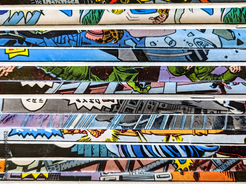 Vintage comic book collection stacked in a pile creates background pattern of colorful lines and shapes on old paper