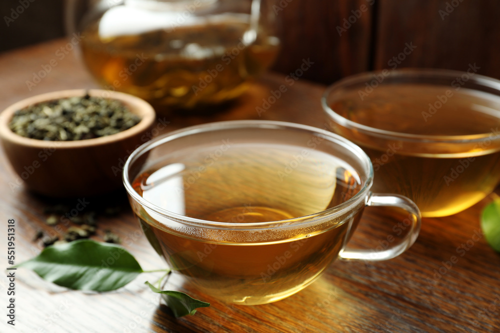Fresh green tea in glass cups and leaves on wooden table