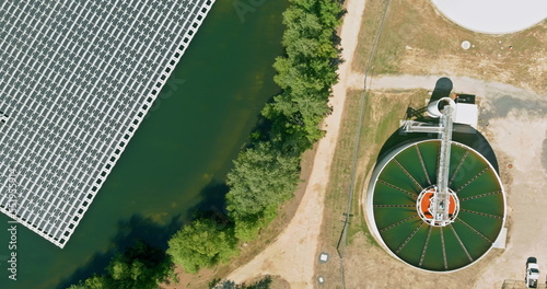 Sewage treatment facilities with aeration water tanks in modern wastewater treatment plant near floating solar panels cell platform system on lake