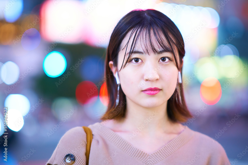 Fototapeta premium 夜の繁華街に立つ若い女性