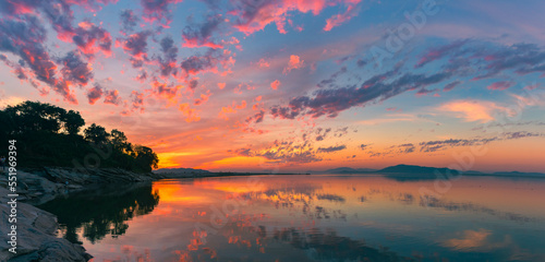 Panorama of a sunset. colourful hues landscape with clouds and hills on the background. beautiful landscape on the banks of Brahmaputra river at Panikhaiti, Assam, India © Devarshi
