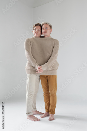 Contemporary shot of identical brothers standing together like siamese twins photo
