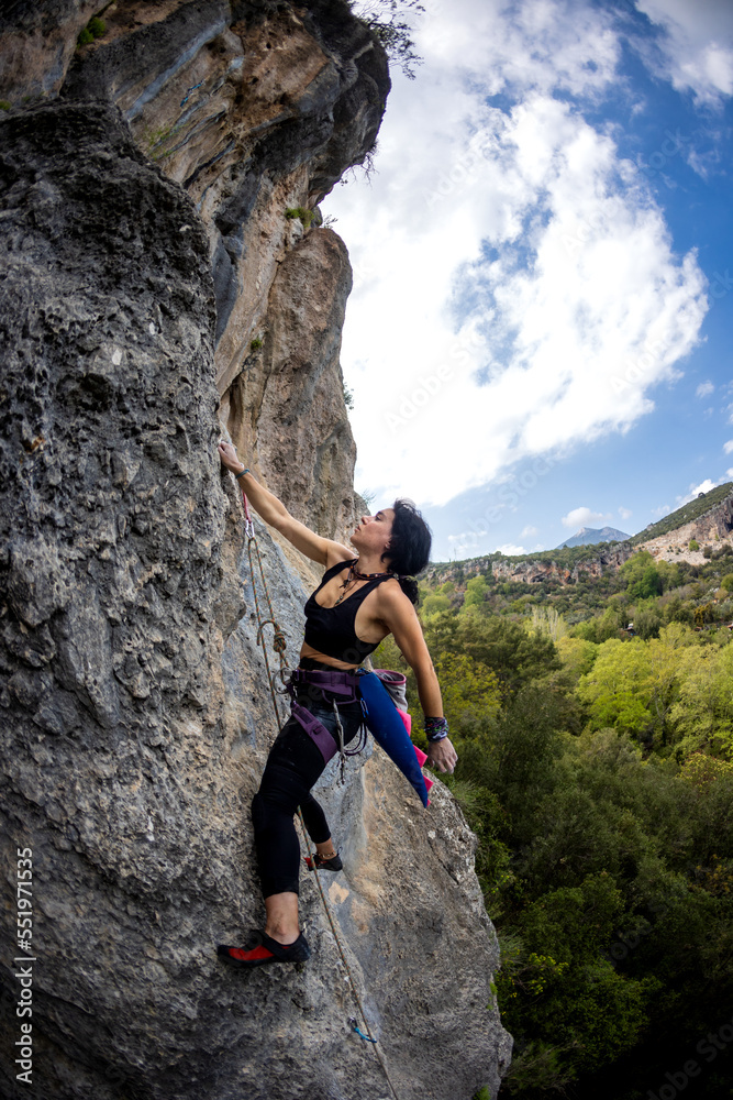 Rock climber girl climbing a rock with a dinosaur tail