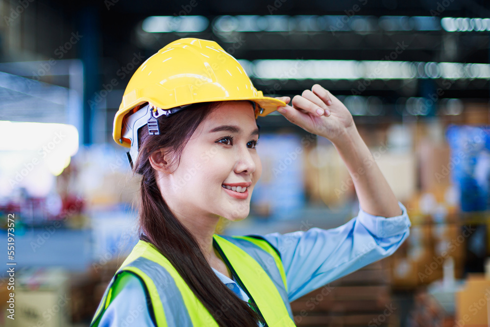 Portrait smart asian female engineer inspector hand hold safety helmet on product management in cardboard box on shelves in warehouse background. construction products with copy space Portrait smart asian female engineer inspector hand hold safety helmet on product management in cardboard box on shelves in warehouse background. construction products with copy space