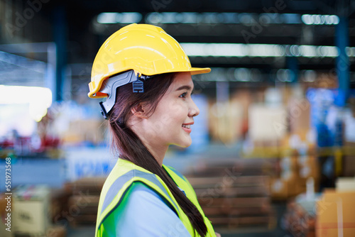 Portrait smart asian female engineer inspector hand hold safety helmet on product management in cardboard box on shelves in warehouse background. construction products with copy space