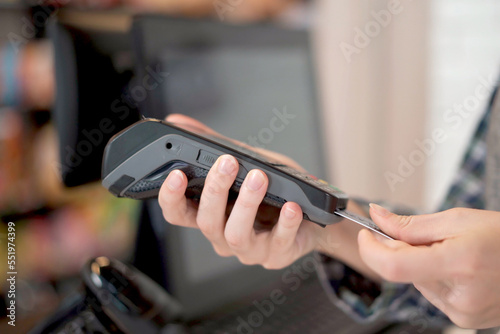 Unrecognizable female shopkeeper cashier using a wireless credit card reader.