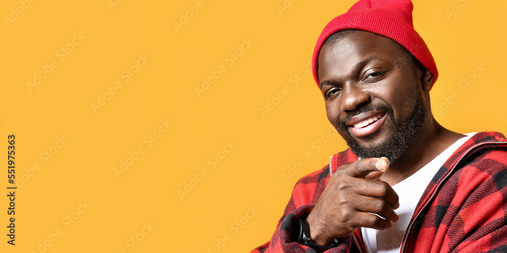 Portrait of cool African-American man pointing at viewer on yellow background with space for text Portrait of cool African-American man pointing at viewer on yellow background with space for text