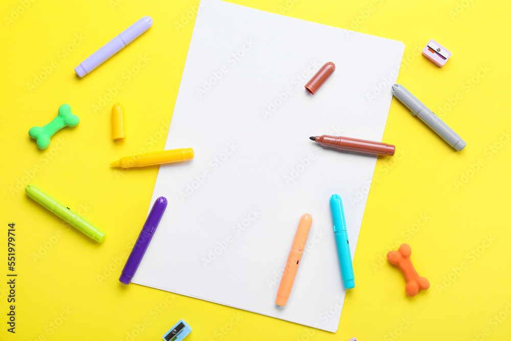 Blank paper sheet with felt-tip pens, erasers and sharpeners on yellow background Blank paper sheet with felt-tip pens, erasers and sharpeners on yellow background