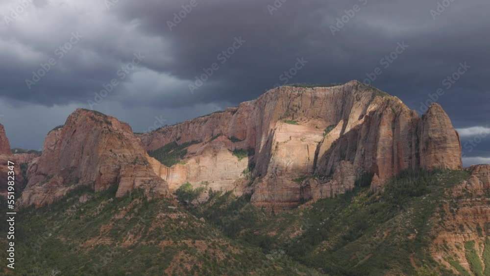 A lightning bolt strikes Timber Top mountain in Kolob Canyon Zion Nat. park Utah during a summer monsoon storm while a band of sunlight breaks through the clouds and lights the side of the mountain. A lightning bolt strikes Timber Top mountain in Kolob Canyon Zion Nat. park Utah during a summer monsoon storm while a band of sunlight breaks through the clouds and lights the side of the mountain.