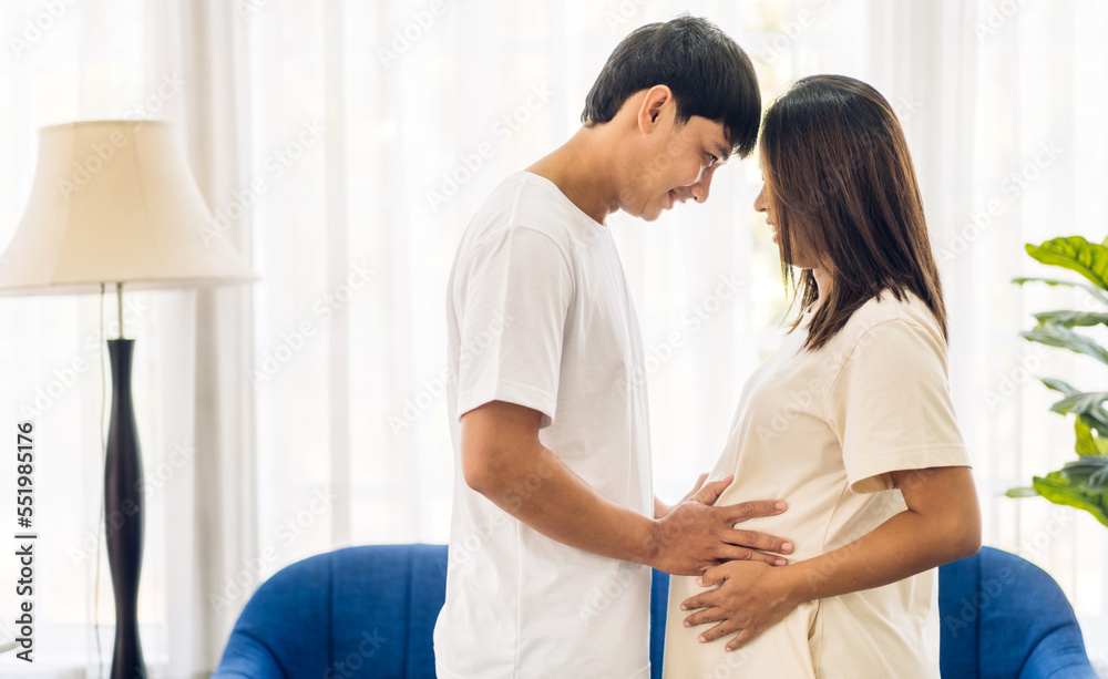 Romantic sweet asian couple husband hugging and smiling beauty asian pregnant wife.Man expecting with woman pregnancy hold to baby in belly at home Romantic sweet asian couple husband hugging and smiling beauty asian pregnant wife.Man expecting with woman pregnancy hold to baby in belly at home