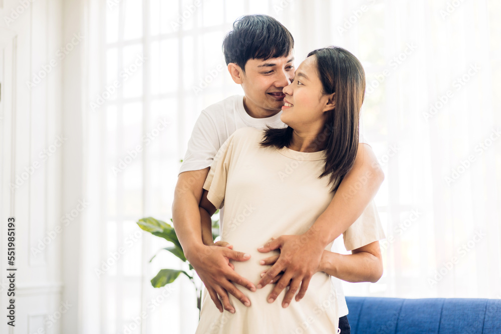 Romantic sweet asian couple husband hugging and smiling beauty asian pregnant wife.Man expecting with woman pregnancy hold to baby in belly at home Romantic sweet asian couple husband hugging and smiling beauty asian pregnant wife.Man expecting with woman pregnancy hold to baby in belly at home