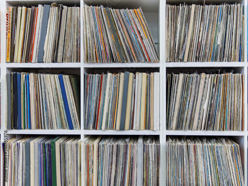 old and vintage vinyl records, a stack of many vinyl records on shelves. Full frame background, side view