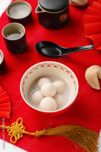 Bowl of tasty tangyuan and Chinese decor on red mat. Dongzhi Festival