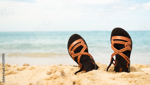 Summer Assessorieses Sandals on Sand Beach with Blur Blue Sea and Blue Sky Background,Slipper for Woman at Coast on Water Shore,Family Tourism Travel Tropical Summer Holidays at Resort.