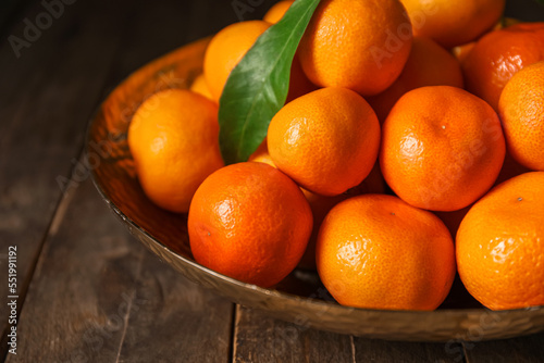 Plate with ripe tangerines on wooden table, closeup