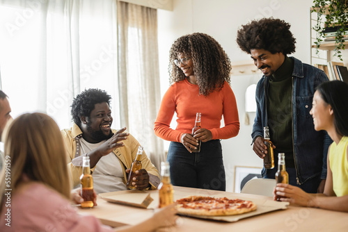 Photography Group of young multiethnic friends having fun at party with pizza and bottles of