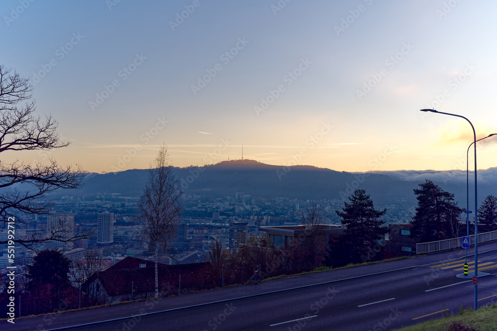 Aerial view over city of Zürich with local mountain Uetliberg in the background and bright sunlight and beautiful autumn evening sun. Photo taken December 6th, 2022, Zurich, Switzerland.