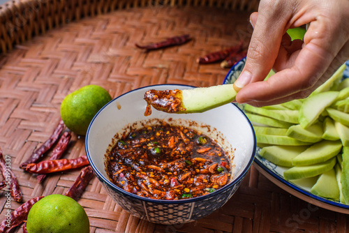 A hands dipping mangoes in sweet fish sauce. Green mango with sweet fish sauce a favorite food at Thailand.