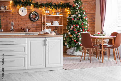 Interior of kitchen with Christmas tree, white counters and dining table © Pixel-Shot