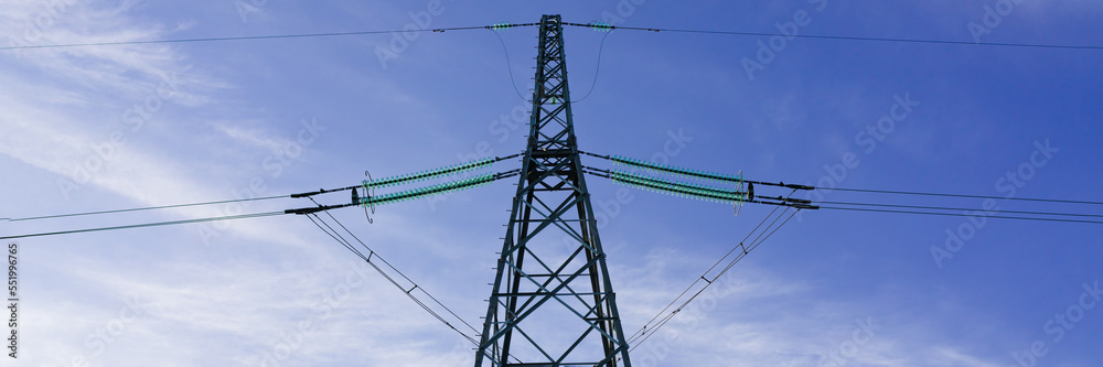 Long distance transmission High-voltage lines pillars on blue sky background