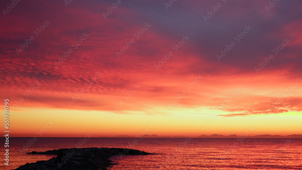 A red sunset over the Tyrrhenian Sea in front of Marina di Cecina on a cool autumn evening