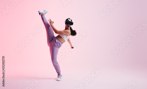 Young woman throwing a kick in a virtual reality game © Jacob Lund
