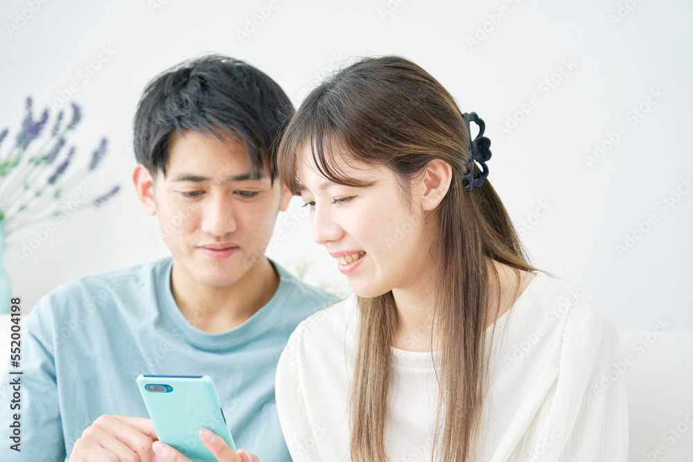 家でスマホを見るカップル 家でスマホを見るカップル