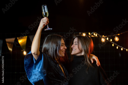 couple of girls looking at each other with a glass of champagne celebrating the end of the year or an anniversary © Cristina