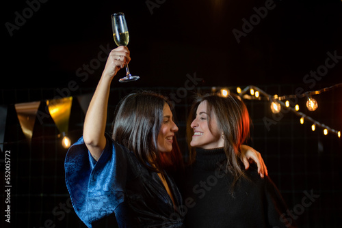 couple of girls looking at each other with a glass of champagne celebrating the end of the year or an anniversary photo