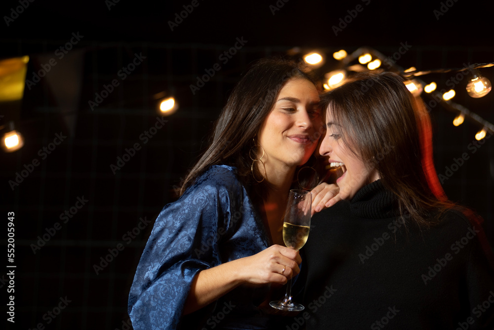 a couple of elegant girls with a glass of champagne talking to each other in a fun and romantic way