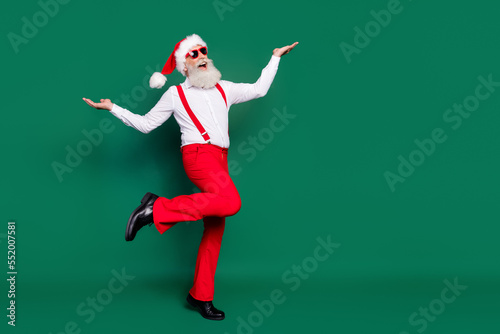 Full length photo of funky impressed senior guy wear x-mas costume walking empty space isolated green color background