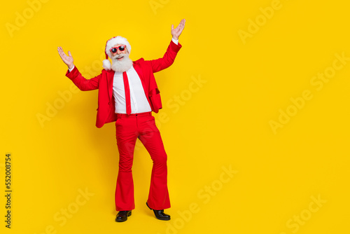 Full size photo of positive excited funky granddad raise hands enjoy event empty space isolated on yellow color background