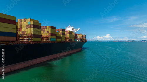 cargo logistic container ship sailing in green sea to import export goods and distributing products to dealer and consumers across worldwide, by container ship aerial view