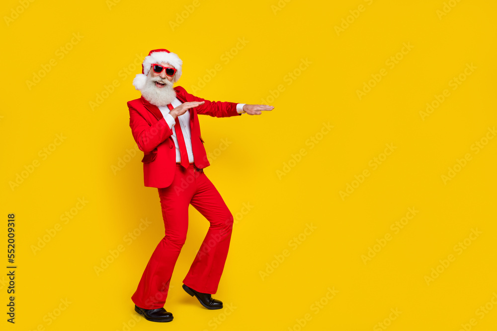 Full length photo of cheerful funny retired guy wear red tux claus hat dancing empty space isolated yellow color background