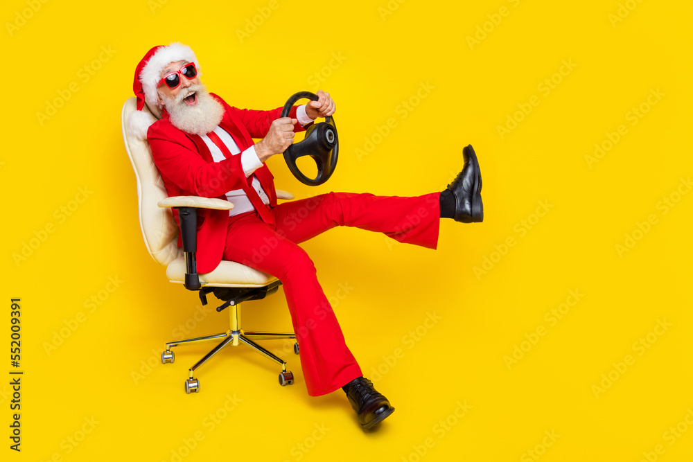 Photo of charming funky retired guy wear red tux claus hat sitting chair auto driver rider isolated yellow color background Photo of charming funky retired guy wear red tux claus hat sitting chair auto driver rider isolated yellow color background