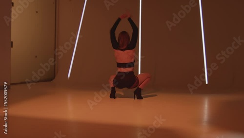 Dancing girl performs modern provocative vogue dance shaking buttocks demonstrating her stretching on studio floor