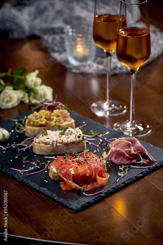 Assorted bruschetta with jamon, salmon and others. Italian appetizers on a black board. Close-up, selective focus