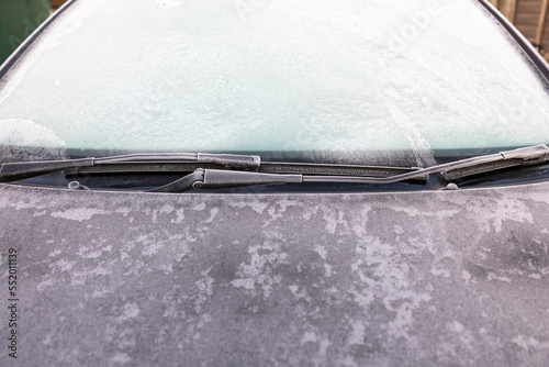 Frozen car windshield covered with ice and snow on a winter day. Close-up view.