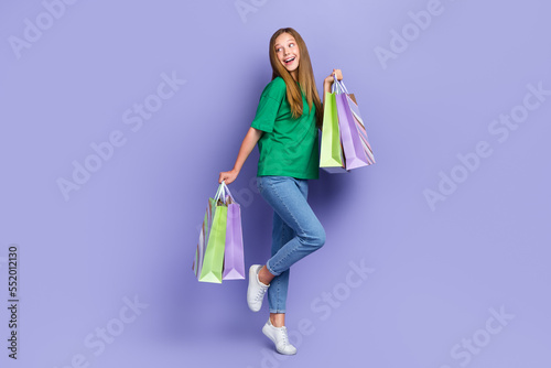 Full length photo of dreamy funny girl dressed green t-shirt holding bargains looking empty space isolated purple color background © deagreez