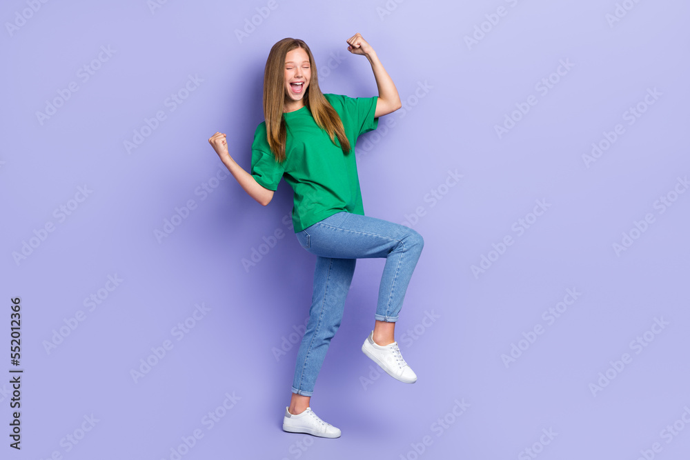 Fototapeta premium Full length photo of lucky funny girl dressed green t-shirt walking rising fists isolated purple color background
