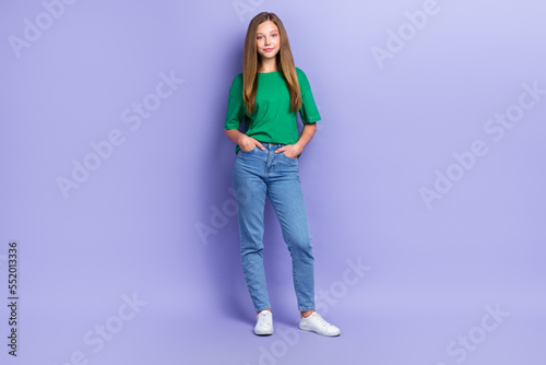 Full length photo of sweet shiny girl dressed green t-shirt walking hands arms pockets smiling isolated purple color background