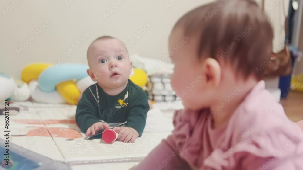 two babies play on the floor in kindergarten. happy family kindergarten kid dream concept. twins baby training hand rattle. newborn baby 6 months old playing on the floor in kindergarten lifestyle two babies play on the floor in kindergarten. happy family kindergarten kid dream concept. twins baby training hand rattle. newborn baby 6 months old playing on the floor in kindergarten lifestyle