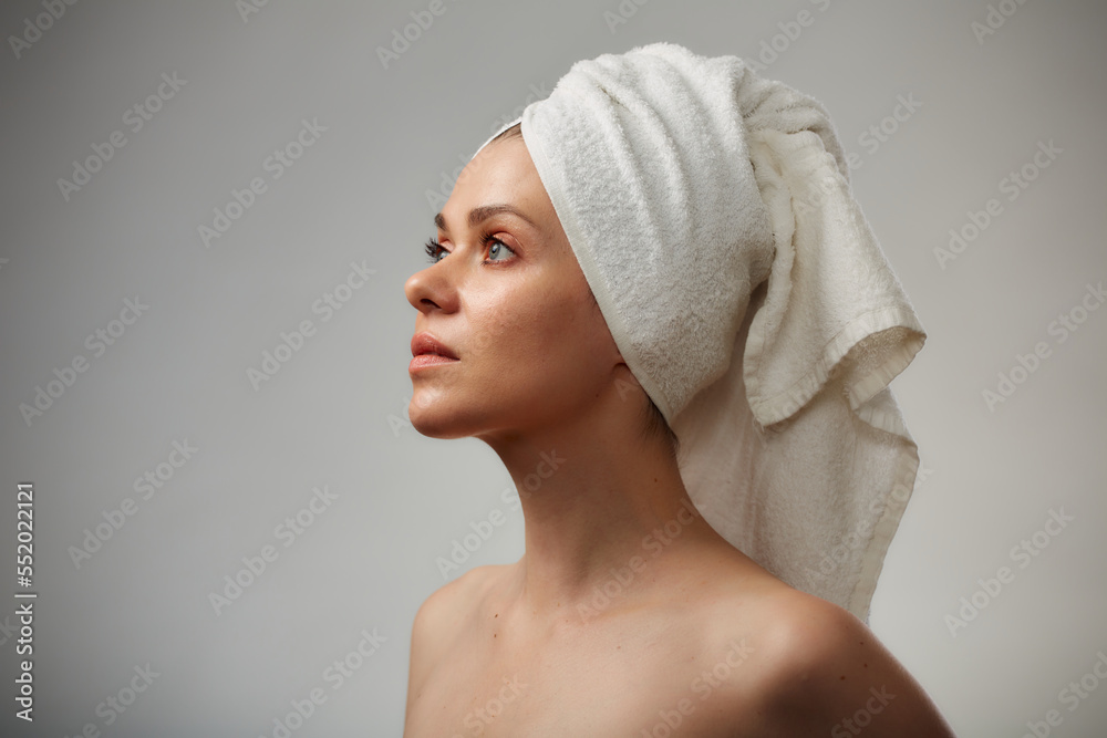 Beauty style profile portrait of young woman with bare shoulders and white towel on head. Isolated studio advertising portrait. Beauty style profile portrait of young woman with bare shoulders and white towel on head. Isolated studio advertising portrait.