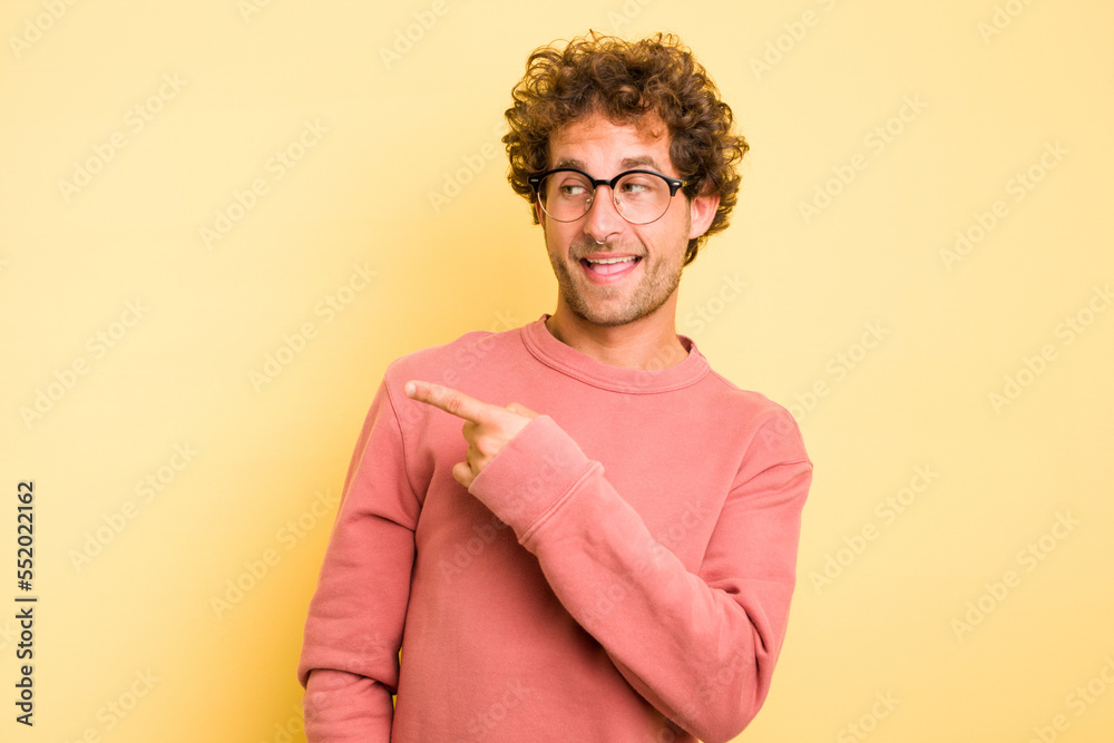 Young smart caucasian man on yellow background looks aside smiling, cheerful and pleasant. Young smart caucasian man on yellow background looks aside smiling, cheerful and pleasant.