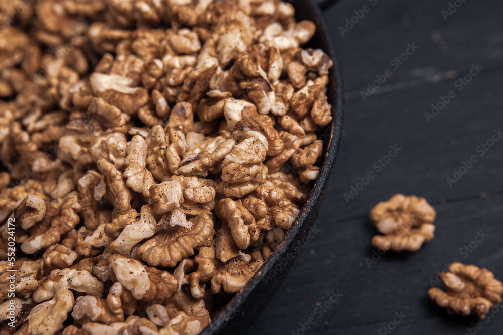 Walnut background. Peeled walnuts on a iron plate on black. walnuts a real super food full of vitamins and vegetable fats