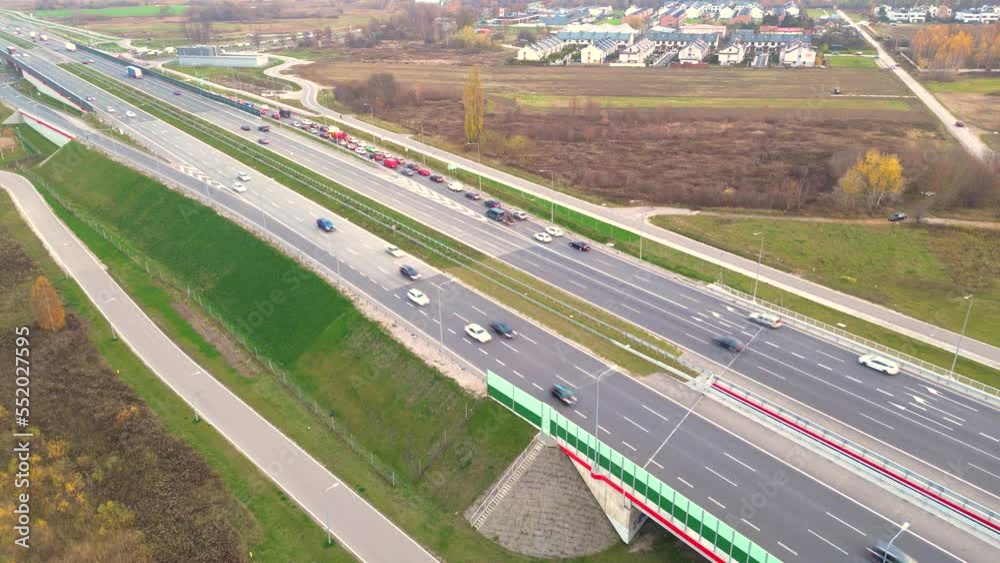 Aerial view of road junction with moving cars. Road interchange or highway intersection with busy urban traffic speeding on the road. Aerial view of road junction with moving cars. Road interchange or highway intersection with busy urban traffic speeding on the road.