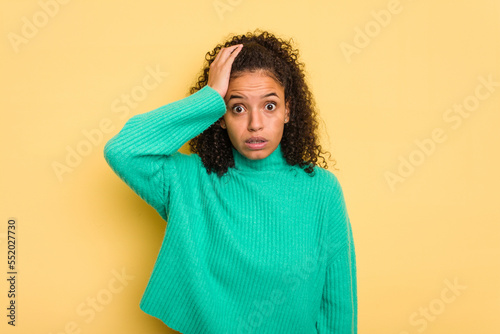 Young Brazilian curly hair cute woman isolated on yellow background being shocked, she has remembered important meeting. © Asier