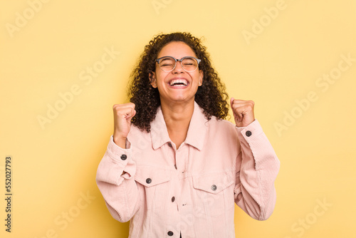 Young Brazilian curly hair cute woman isolated on yellow background celebrating a victory, passion and enthusiasm, happy expression. photo